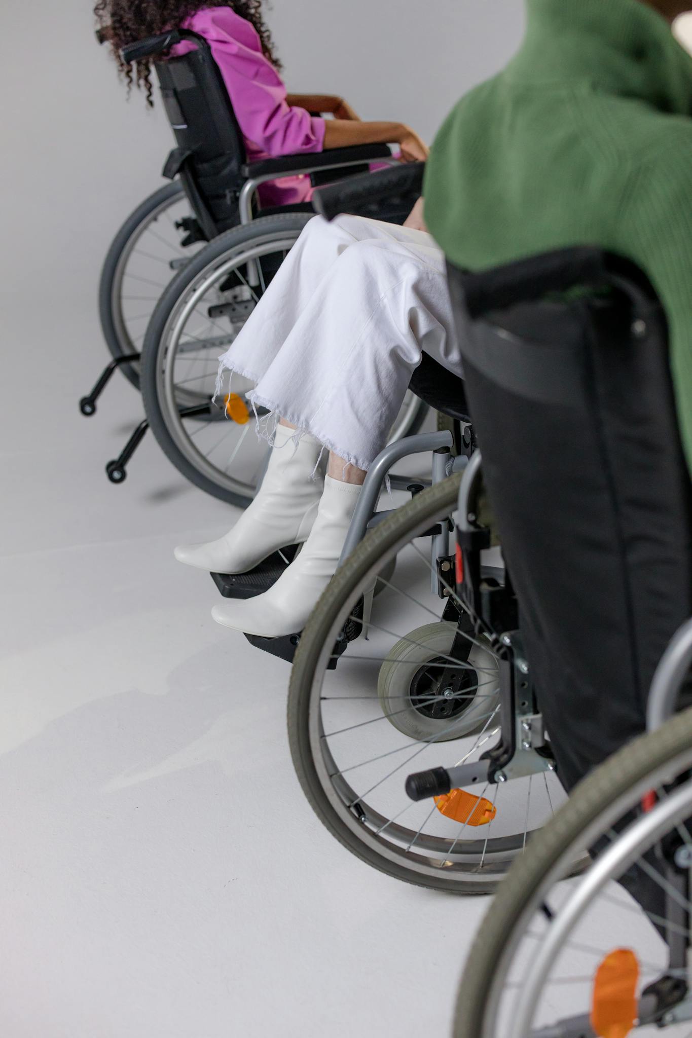 Stylish people in wheelchairs wearing trendy outfits for a modern fashion shoot.